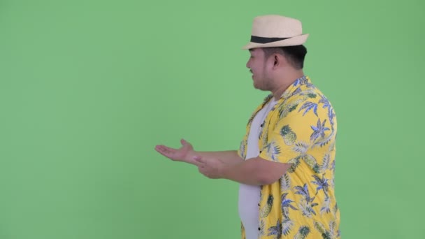 幸せな若い太りすぎのアジアの観光客の男は背中に示し、親指を与える — ストック動画