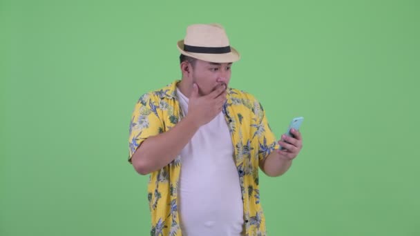 Feliz joven sobrepeso asiático turista hombre usando el teléfono y buscando sorprendido — Vídeo de stock