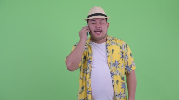 Happy young overweight Asian tourist man talking on the phone — Stock Video