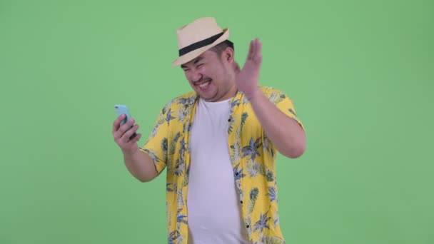 Felice giovane sovrappeso asiatico turista uomo video chiamata e mostrando telefono — Video Stock