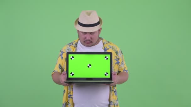 Benadrukte jonge overgewicht Aziatische toerist man toont laptop — Stockvideo