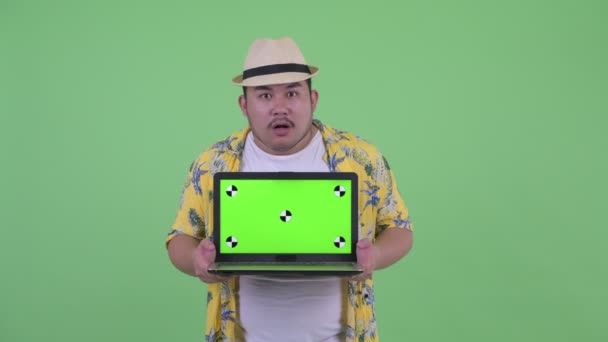 Šťastná mladá nadváha asijský turistický muž, který hovoří při zobrazování přenosného počítače — Stock video