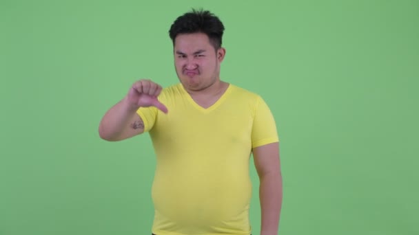 Estresado joven sobrepeso asiático hombre dando pulgares abajo — Vídeos de Stock