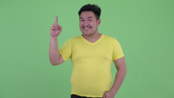 Lycklig ung övervikt asiatisk man pekar upp — Stockvideo