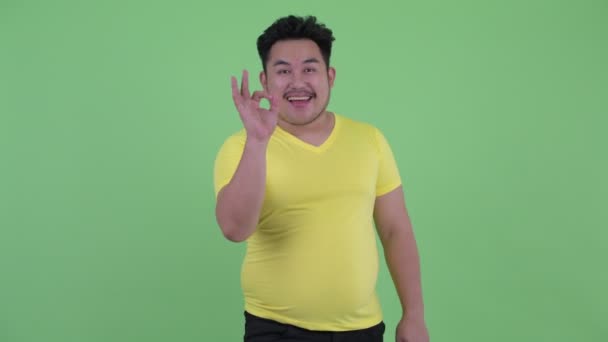 Lycklig ung övervikt asiatisk man med OK skylt — Stockvideo
