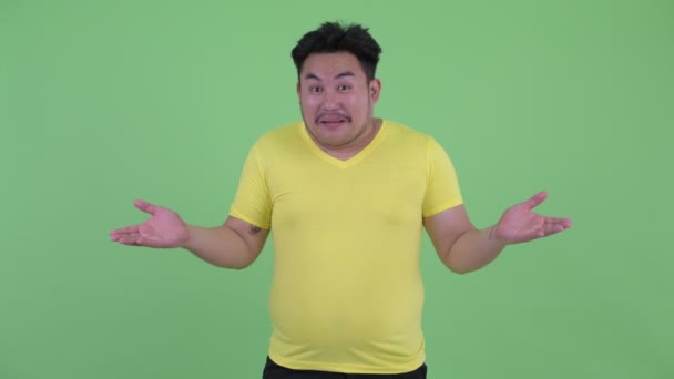 Feliz joven sobrepeso asiático hombre encogiéndose de hombros y buscando culpable — Vídeos de Stock