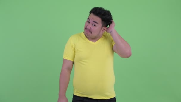 Kafası kaşıyan ve omuz silken genç kilolu Asyalı adam Confused — Stok video