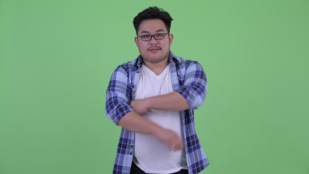 Boldog fiatal túlsúlyos ázsiai csípő ember mosolyogva a karok keresztbe — Stock videók