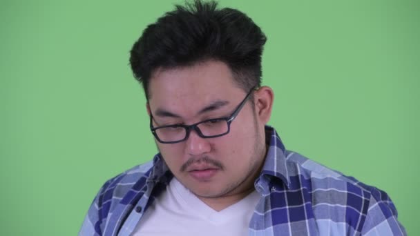 Face de estressado jovem acima do peso asiático hipster homem pensando e olhando para baixo — Vídeo de Stock