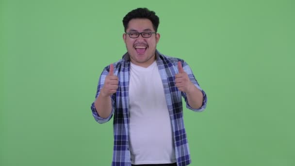 Happy young overweight Asian hipster man giving thumbs up and looking excited — Stock Video