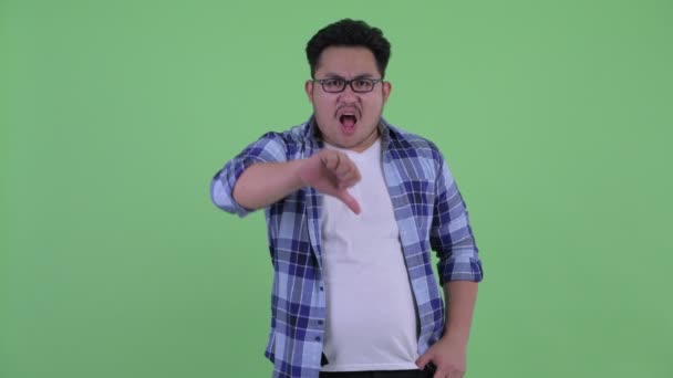 Arga unga överviktiga asiatiska hipster man ger tummen ner — Stockvideo
