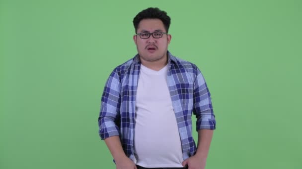 Ledsen ung överviktiga asiatiska hipster man ger tummen ner — Stockvideo