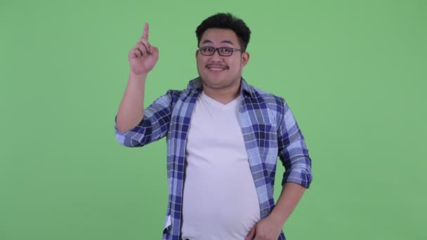 幸せな若い太りすぎアジアのヒップスターの男が指差す — ストック動画