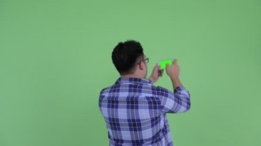 Genç kilolu Asyalı hipster adam telefon ile fotoğraf çekmek Arka görüş