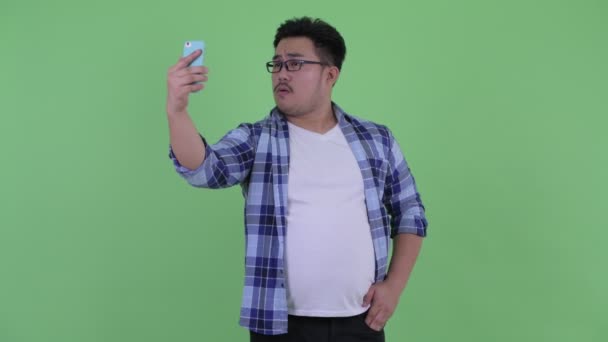 Feliz jovem acima do peso asiático hipster homem vídeo chamada — Vídeo de Stock