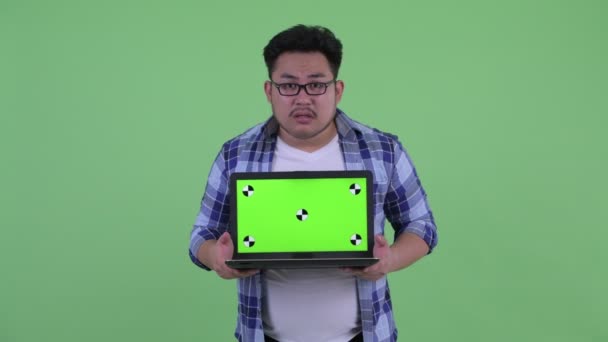 Benadrukte jonge overgewicht Aziatische hipster man toont laptop — Stockvideo