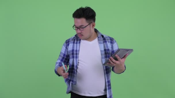 Heureux jeune homme hipster asiatique en surpoids utilisant le téléphone et la tablette numérique — Video