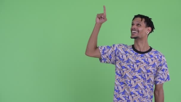 Glücklicher junger gutaussehender afrikanischer Mann zeigt nach oben und sieht aufgeregt aus — Stockvideo