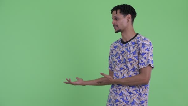 Glücklich junge gutaussehende afrikanische Mann spricht, während zeigen, um zurück — Stockvideo