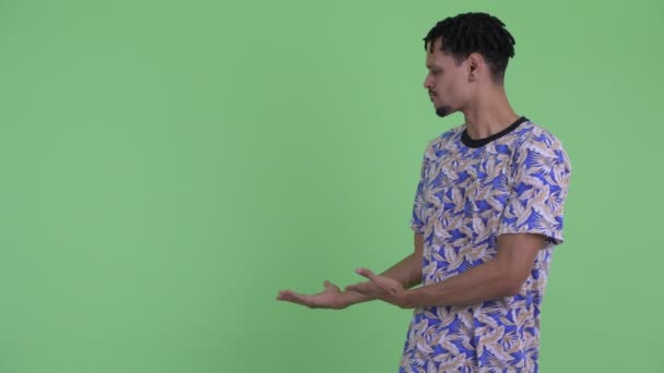 Стрессовый молодой африканский мужчина с дредами, показывающими спину — стоковое видео
