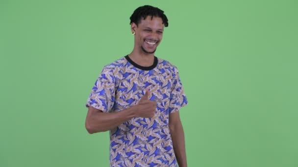 Feliz jovem e bonito homem africano dando polegares para cima e olhando animado — Vídeo de Stock