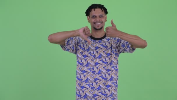 Verward jonge Afrikaanse man kiezen tussen duim omhoog en duimen naar beneden — Stockvideo