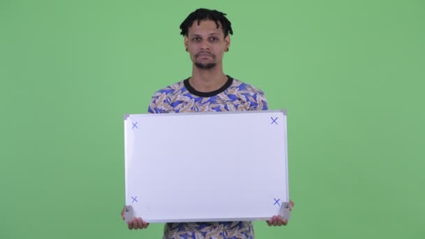 ホワイトボードを持ちながら考える幸せな若いハンサムなアフリカ人男性 — ストック動画
