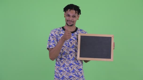 Szczęśliwy młody afrykański mężczyzna trzyma tablica i daje kciuki w górę — Wideo stockowe
