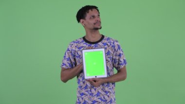 Mutlu genç yakışıklı Afrikalı adam dijital tablet gösterirken düşünme