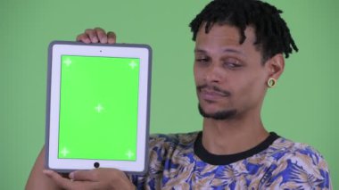 Dijital tablet gösteren mutlu genç yakışıklı Afrikalı adamın yüzü