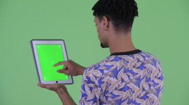 Dijital tablet kullanarak mutlu genç yakışıklı Afrikalı adam Arka görüş
