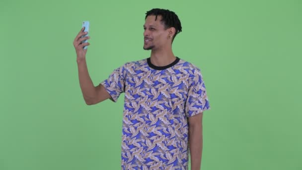 Gelukkig jonge knappe Afrikaanse man videobellen en tonen telefoon — Stockvideo