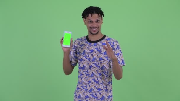 Feliz joven guapo africano hombre mostrando el teléfono y dando pulgares hacia arriba — Vídeos de Stock