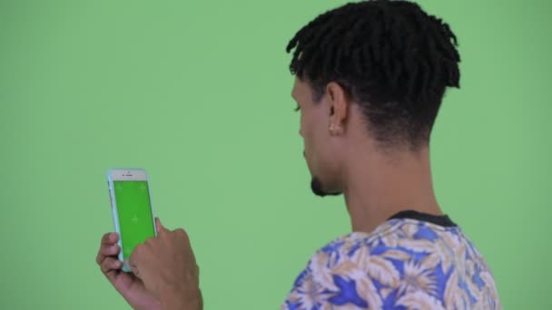 Close-up Achteraanzicht van gelukkige jonge Afrikaanse man die telefoon gebruikt — Stockvideo