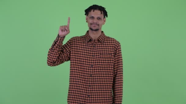 Feliz joven apuesto hombre africano señalando hacia arriba — Vídeos de Stock