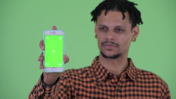 Gezicht van gelukkig jonge knappe Afrikaanse man tonen telefoon — Stockvideo