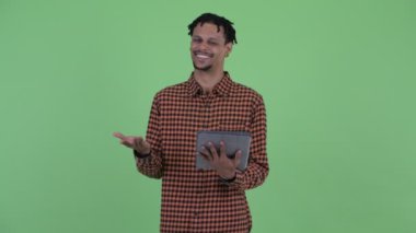 Mutlu genç yakışıklı Afrikalı adam dijital tablet kullanırken konuşuyor