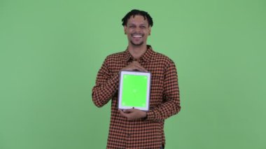 Mutlu genç yakışıklı Afrikalı adam dijital tablet gösterirken konuşuyor