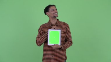 Mutlu genç yakışıklı Afrikalı adam dijital tablet gösterirken düşünme