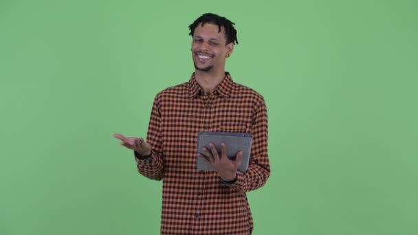 Mutlu genç yakışıklı Afrikalı adam dijital tablet kullanırken konuşuyor — Stok video