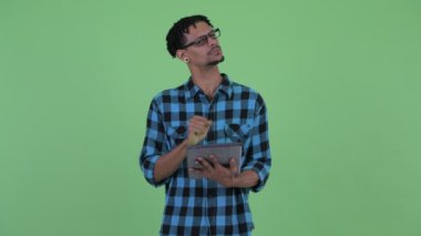 Mutlu genç Afrikalı hipster adam dijital tablet kullanırken düşünme