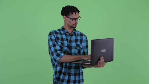 Feliz jovem Africano hipster homem pensando ao usar laptop — Vídeo de Stock