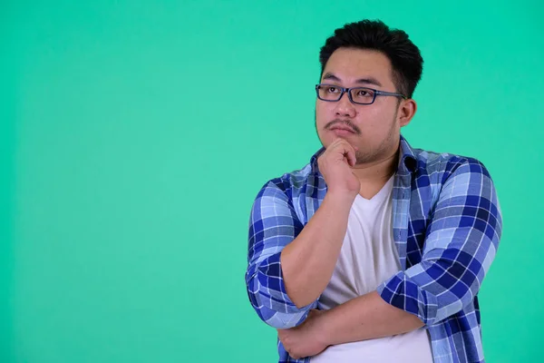 Genç kilolu Asya hipster adam düşünme ve yukarı bakıyor