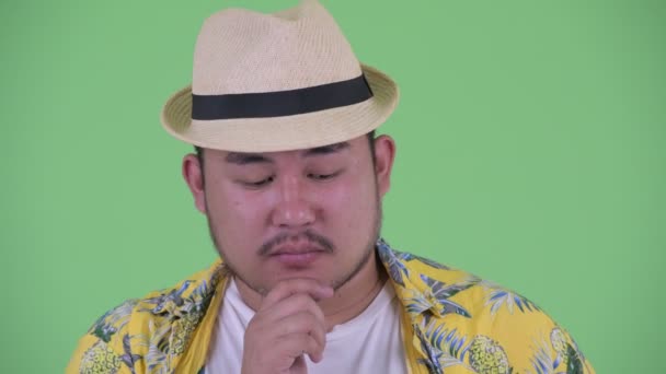 Лицо грустного молодого толстого азиатского туриста, думающего — стоковое видео