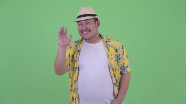 Mutlu genç kilolu Asyalı turist adam el sallayarak — Stok video