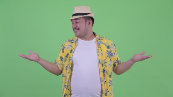 Szczęśliwy młody nadwagą azjatycki turysta mężczyzna porównując coś — Wideo stockowe