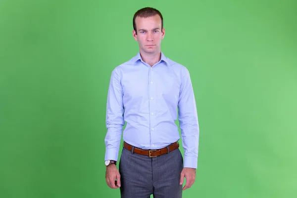 Portret biznesmena stojący na zielonym tle — Zdjęcie stockowe