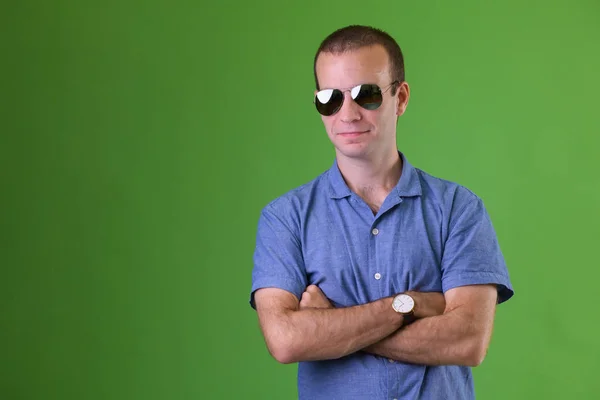 Портрет бізнесмена в сонцезахисних окулярах з руками, схрещеними на зеленому тлі — стокове фото
