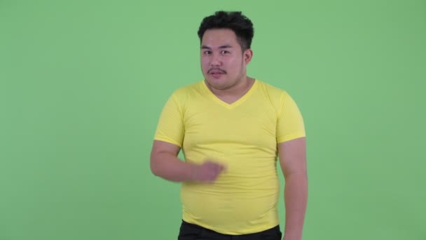 Счастливый молодой толстый азиат с пальцем на губах — стоковое видео