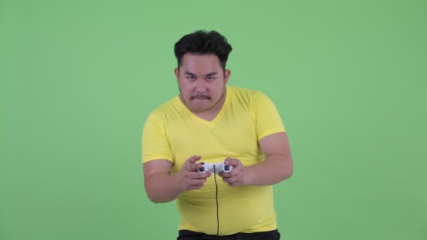 Glücklich junge übergewichtige asiatische Mann spielen Spiele und gewinnen — Stockvideo